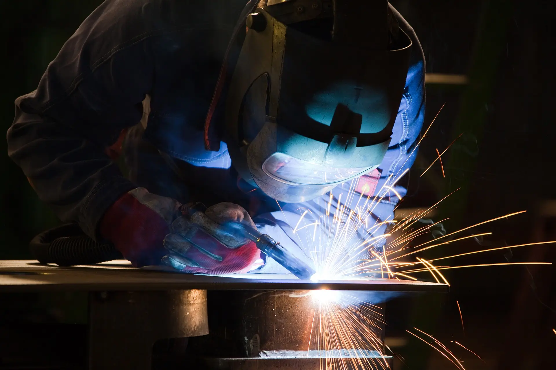 Schweißer mit Schweißhelm bei der Arbeit, Funkenflug